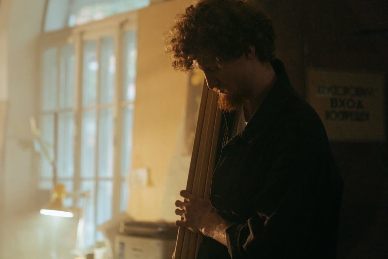 journey Silhouette of a craftsman holding wood in a sunlit workshop, embodying craft and tradition.