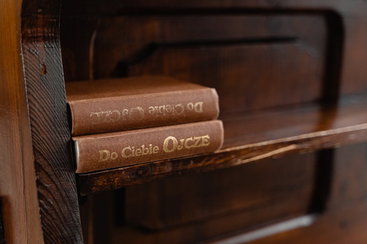 who-we-are A cozy rustic wooden shelf displaying vintage books with gold embossed titles.